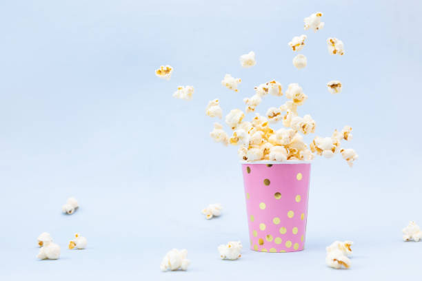 Flying Popcorn in a bright glass and on a blue background. stock photo