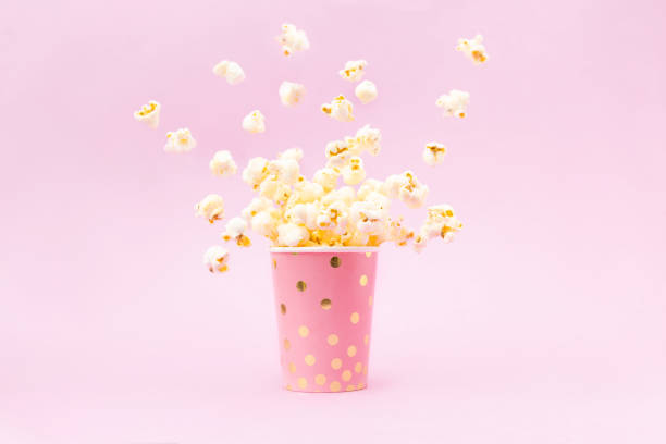 Flying Popcorn in a bright glass and on a pink background. stock photo