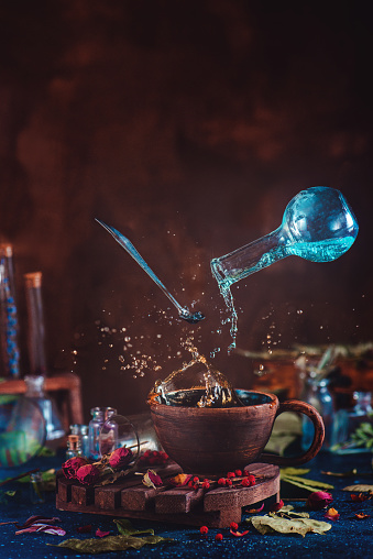 flying-potion-bottle-with-pouring-liquid-in-a-magical-still-life-picture-id835776054