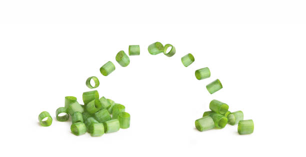 Flying slices of chopped green onion on a white background stock photo