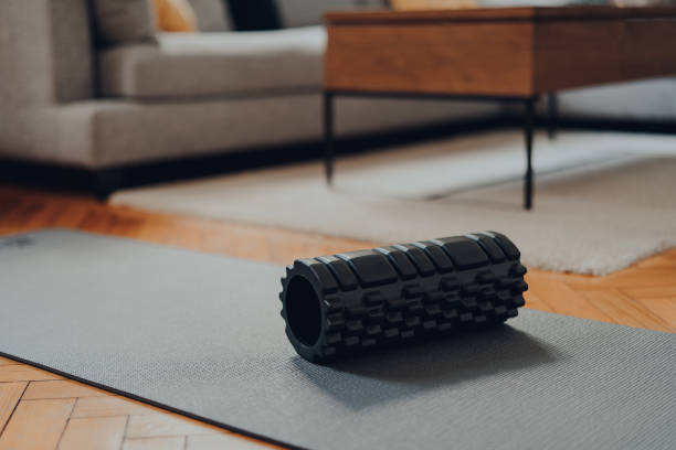 Foam roller and a fitness mat within modern living space, selective focus. stock photo
