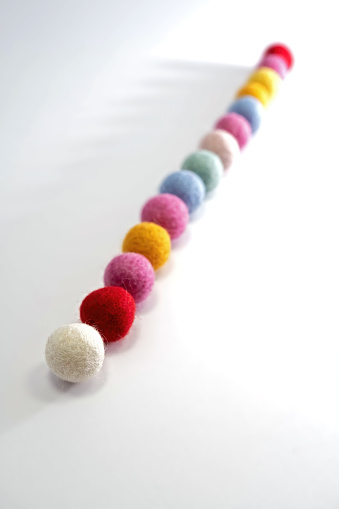 colorful felt balls in a row, focus in the foreground