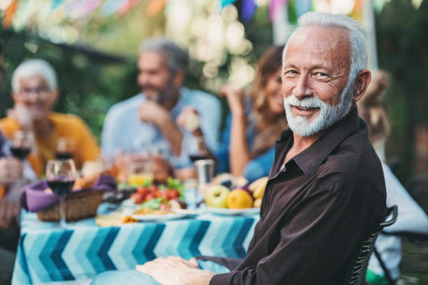 Focus on a smiling senior man on a family celebration Multi-generation family gathered for a celebration in the garden 50 59 years stock pictures, royalty-free photos & images