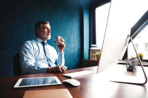 Focused mature businessman deep in thought while sitting at a table in modern office. Focused mature businessman deep in thought while sitting at a table in modern office ceo stock pictures, royalty-free photos & images