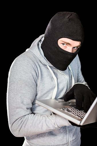 focused-thief-with-hood-typing-on-laptop-picture-id845608926