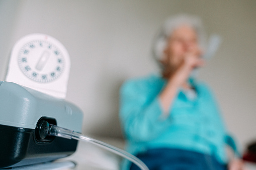 A Wind-Up Timer Counts Down in the Foreground as a Senior Caucasian Woman Sits at Home Using a Nebulizer to Inhale Medication to Treat Asthma or Open Up Lung Airways

Nebulizer Inhalers often use treatments such as Budesonide, Flunisolide, Fluticasone, and Triamcinolone. In other cases, they will also utilize Bronchodilators such as albuterol, Formoterol, Levalbuterol, and Salmeterol to open airways.