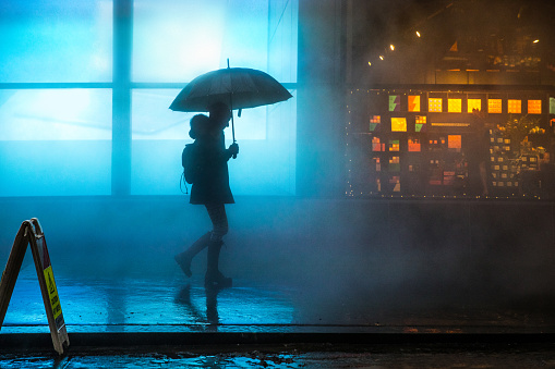 Foggy downtown in Lower Manhattan a woman walking under the rain in the dark