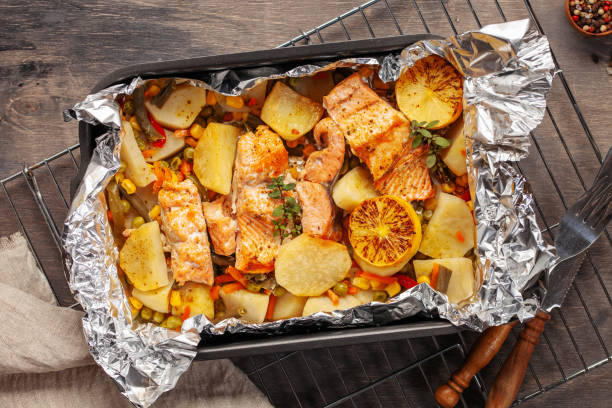 Foil pack dinners. Salmon with vegetables baked in foil. Dietary food. Top view stock photo