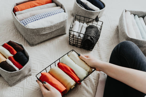 Folding clothes and organizing stuff in boxes and baskets. Concept of tidiness, minimalist lifestyle and japanese t-shirt folding system. Wardrobe storage system. Clean up clothes with konmari method (Marie Kondo). Clothes neatly folded in bedroom housework photos stock pictures, royalty-free photos & images