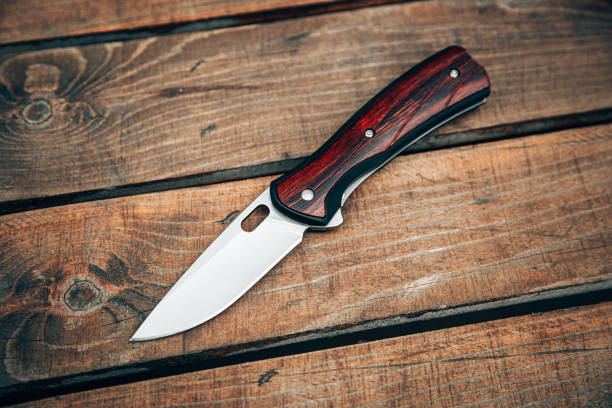 Folding pocket knife with wooden handle. A small knife on a wooden surface. stock photo