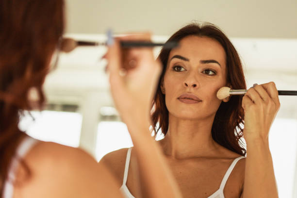 Following her morning make-up routine Selective focus of mature woman using a make-up brush to apply foundation on her cheeks. applying blush stock pictures, royalty-free photos & images