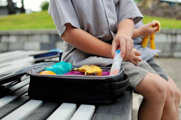 Food Allergy Young boy with a packed lunch takes out his anaphylaxis auto injector. adrenaline stock pictures, royalty-free photos & images