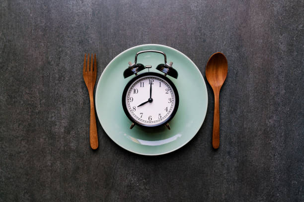 Food clock spoon and fork, Healthy food concept on black background stock photo