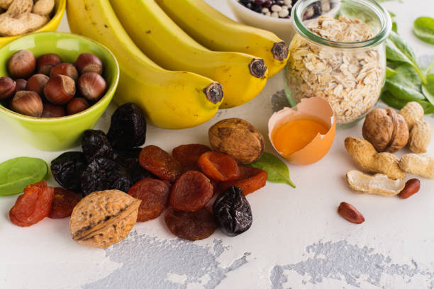 Food containing potassium Products rich of potassium - K. Bananas, spinach, nuts, grains, dried fruits overs stone table. Space for text potassium stock pictures, royalty-free photos & images