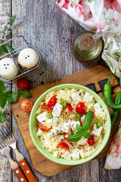 Food dieting concept, tabbouleh salad. Couscous salad with feta cheese, tomatoes, basil and chili on a rustic wooden table. Top view flat lay. Copy space. stock photo