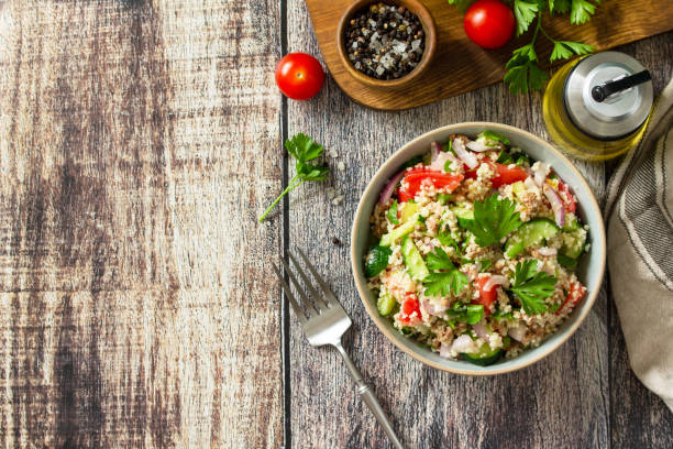 Food dieting concept, tuna salad. Couscous salad with conserved tuna, tomatoes, cucumbers and purple onions on rustic wooden table. Top view flat lay. Copy space. stock photo