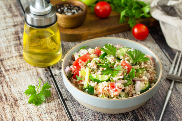 Food dieting concept, tuna salad. Couscous salad with conserved tuna, tomatoes, cucumbers and purple onions on rustic wooden table. stock photo