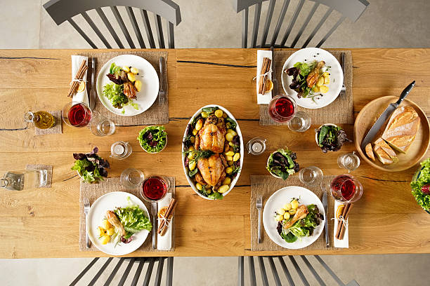 Food on table Top view of two roasted chicken in a bowl on lunch table. High angle view of dining table with salad and red wine. dining table stock pictures, royalty-free photos & images
