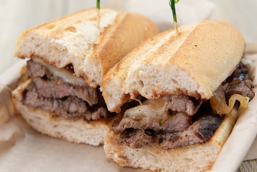 Two halves of a cut tri tip steak sandwich seasoned and arranged on a toasted french roll.