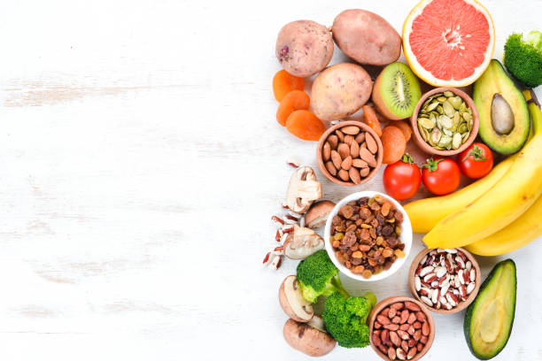 Foods containing natural potassium. K: Potatoes, mushrooms, banana, tomatoes, nuts, beans, broccoli, avocados. Top view. On a white wooden background. Foods containing natural potassium. K: Potatoes, mushrooms, banana, tomatoes, nuts, beans, broccoli, avocados. Top view. On a white wooden background. potassium stock pictures, royalty-free photos & images