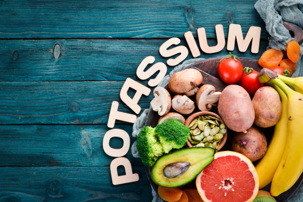 Foods containing natural potassium. K: Potatoes, mushrooms, banana, tomatoes, nuts, beans, broccoli, avocados. Top view. On a blue wooden background. Foods containing natural potassium. K: Potatoes, mushrooms, banana, tomatoes, nuts, beans, broccoli, avocados. Top view. On a blue wooden background. potassium stock pictures, royalty-free photos & images