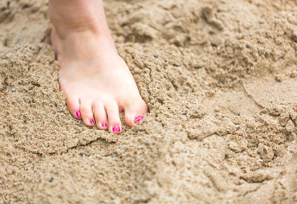 Foot in the sand Young woman with her foot in the sand at the beach human feet buried in sand. summer beach stock pictures, royalty-free photos & images