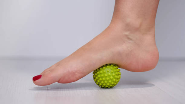 foot step on massage ball to relieve Plantar fasciitis or heel pain. woman with red pedicure massaging trigger points on her foot foot step on massage ball to relieve Plantar fasciitis or heel pain. woman with red pedicure massaging trigger points on her foot. plantar fasciitis stock pictures, royalty-free photos & images