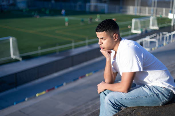 Football fan bored while sitting on stadium bleachers stock photo