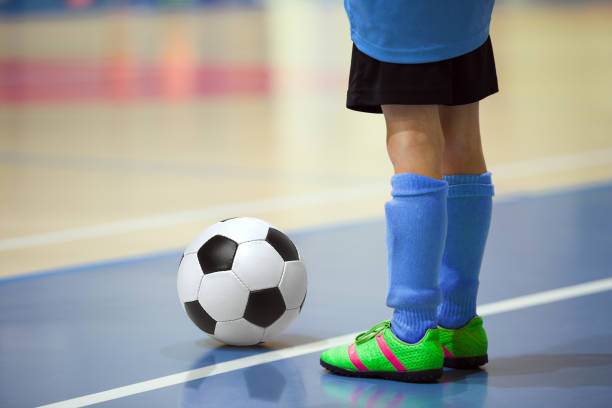 football futsal training for children. indoor soccer young player with a soccer ball in a sports hall. player in blue uniform. sport background. - futsal imagens e fotografias de stock