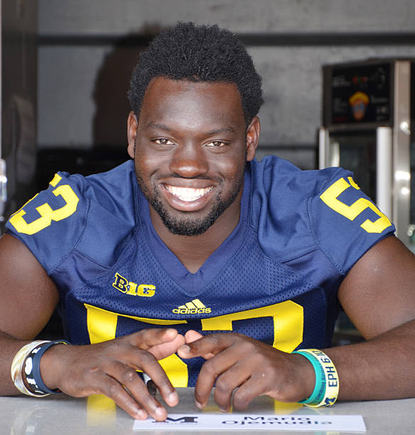 UM football player 53 Mario Ojemudia Ann Arbor, MI - August 10, 2014: University of Michigan football player Mario Ojemudia pauses between autographs at Michigan Football Youth Day on August 10, 2014 in Ann Arbor, MI. michigan football stock pictures, royalty-free photos & images