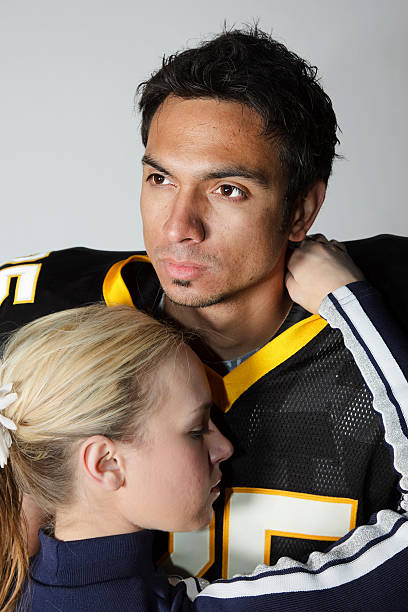Football Player and Cheerleader A football player hugging a cheerleader. teenage boys men blond hair muscular build stock pictures, royalty-free photos & images