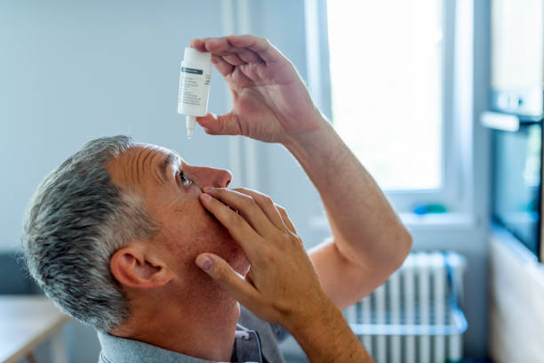For better vision Photo of a mature man putting eye drop. Close-up Of A Mature Man Putting Eye Drops In Eyes. Gray hair Man putting eye drop. Closeup view of an elderly person using a bottle of eyedrops in her eyes, sick old man suffering from the irritated eye. optical symptoms, health concept. dry stock pictures, royalty-free photos & images
