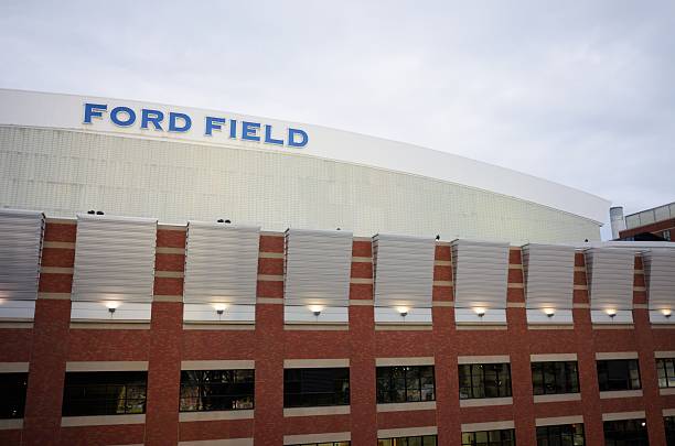 Ford field sign Detroit, Michigan, USA - August 8, 2015: Photograph of illuminated Ford Field football stadium with sign over arched roof around sunset.  Stadium located on Brush Street in Detroit, Michigan. michigan football stock pictures, royalty-free photos & images