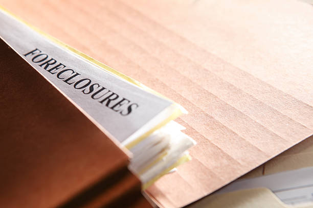 Foreclosure documents stuffed into a brown file folder A file folder stuffed with paperwork pertaining to foreclosure proceedings. Shot with shallow depth of field. foreclosure stock pictures, royalty-free photos & images