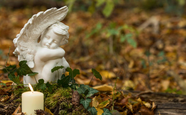 Forest burial, angel with candles on tree trunk Forest cemetery, angel with candles in forest, nature funeral funerary urn stock pictures, royalty-free photos & images