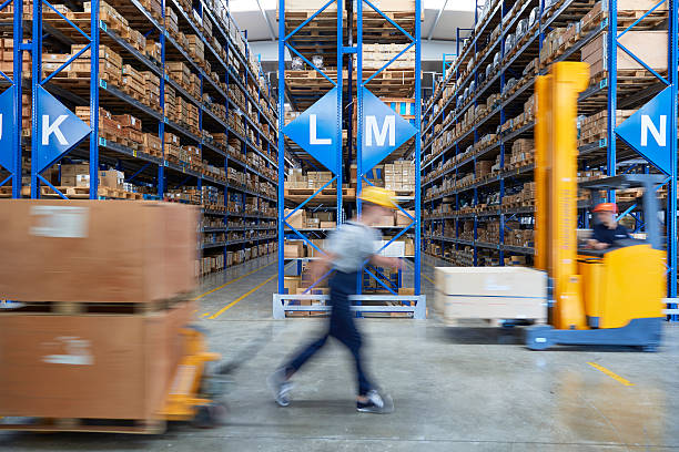 Forklifts carrying cardboard box in warehouse. stock photo