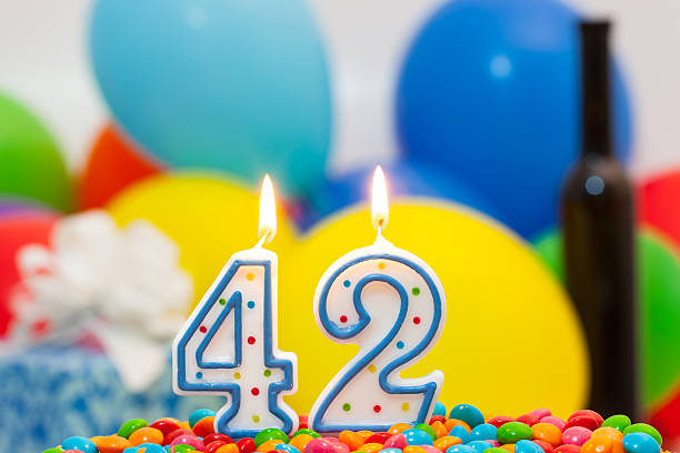 forty-two  birthday. 42th birthday with lighted candles. Balloons, gift box and bottle of wine in background. happy birthday wine bottle stock pictures, royalty-free photos & images