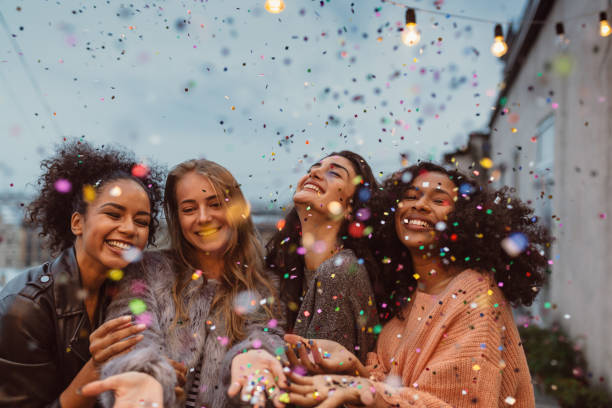 Four beautiful women standing at a terrace under confetti. Four beautiful women standing at a terrace under confetti. only women stock pictures, royalty-free photos & images