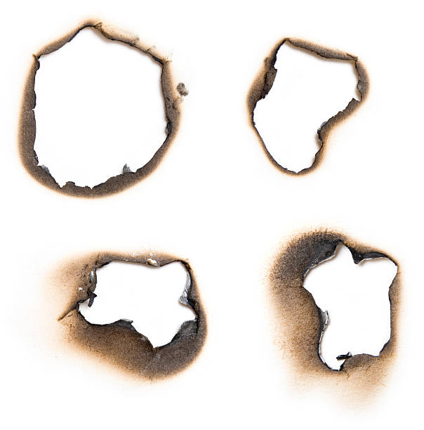 Four burn holes on a paper in white stock photo