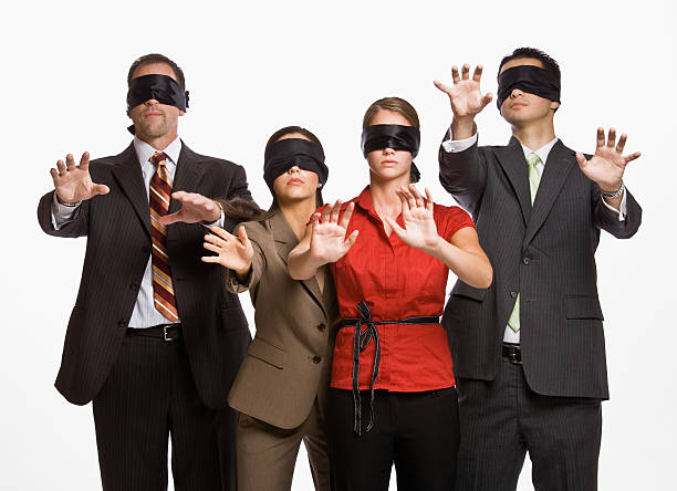 Four business people in blindfolds holding out their arms stock photo