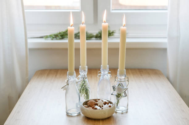 Four candles in bottles is lit for Advent, Christmas cookies and decoration on a table near the window, copy space, selected focus stock photo