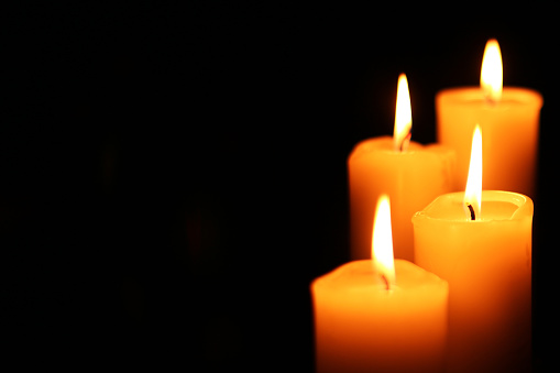 Four big different burning candles. Bright light on dark background. RIP darkness template. Birthday party. Romantic evening on Valentine.