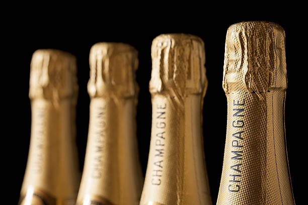 Four champagne bottles with gold wrappings stock photo