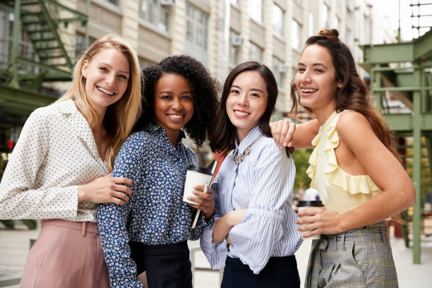 cuatro compañeros de trabajo mujer sonriendo a la cámara fuera de - mujeres jóvenes fotografías e imágenes de stock