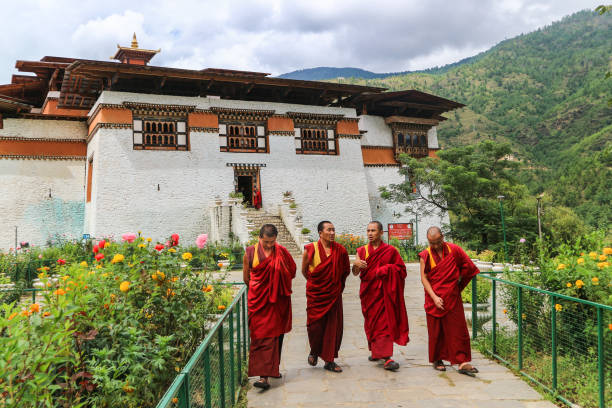 Four monks walking in the garden of Simtokha Dzong, Thimphu, Bhutan stock photo