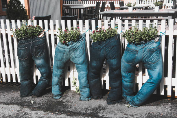 Four pairs of jeans filled with earth, plants and flowers Nature, objects, funny recycling ideas organic jeans stock pictures, royalty-free photos & images