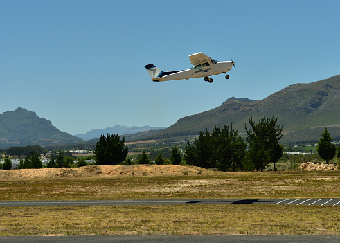 A four seater small plane taking off with Stellenbosch Mountains in the background