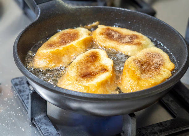 Four torrijas (spanish french toasts) being fried on a stove pan in a home kitchen. stock photo