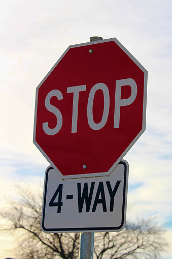 Four Way Stop Sign Against Cloudy Sky