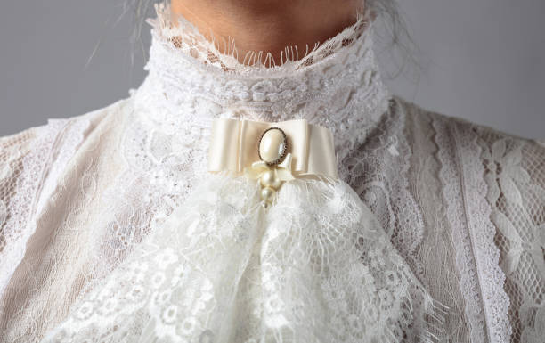 Fragment of a Victorian dress with a brooch. Fragment of a Victorian dress with a brooch. White blouse with lace, embroidery and high collar. period costume stock pictures, royalty-free photos & images